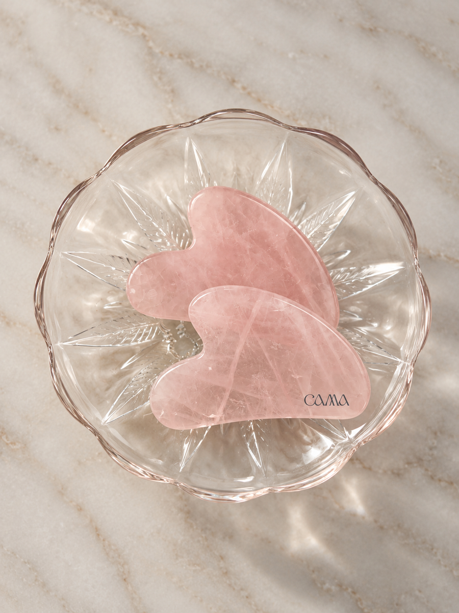 To gua sha-steiner i rosekvarts i en glasskål
