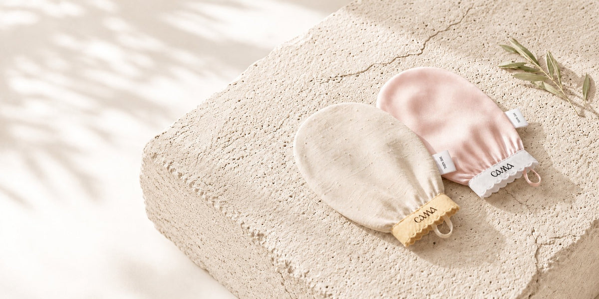 To eksfolierende silkevotter fra Cama Reform i beige og rosa på en steinflate